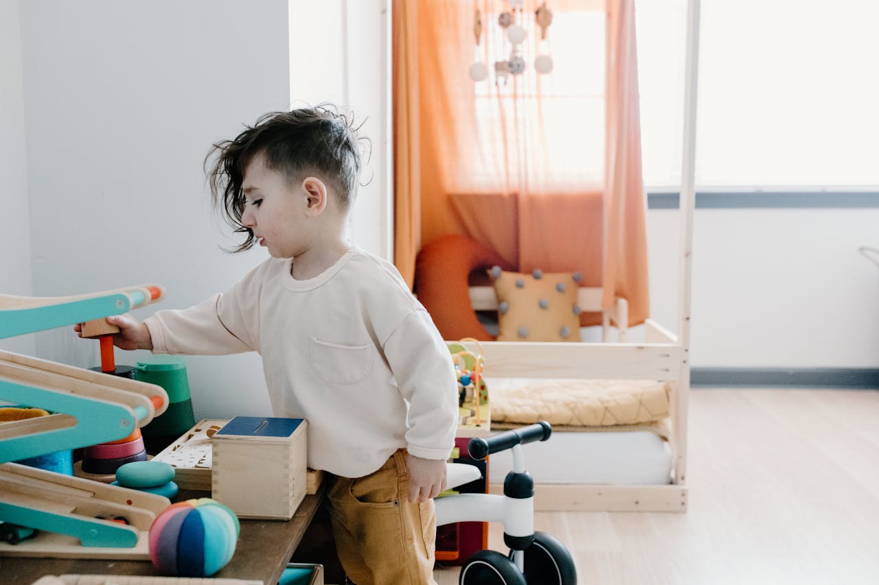 A young child engages with colorful wooden toys in a cozy indoor setting.