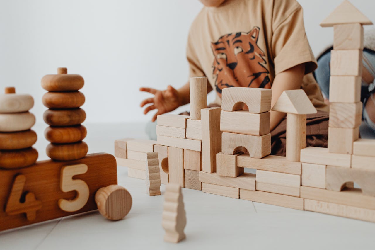 A child is building structures with wooden blocks in a playroom, focusing on creativity and learning.