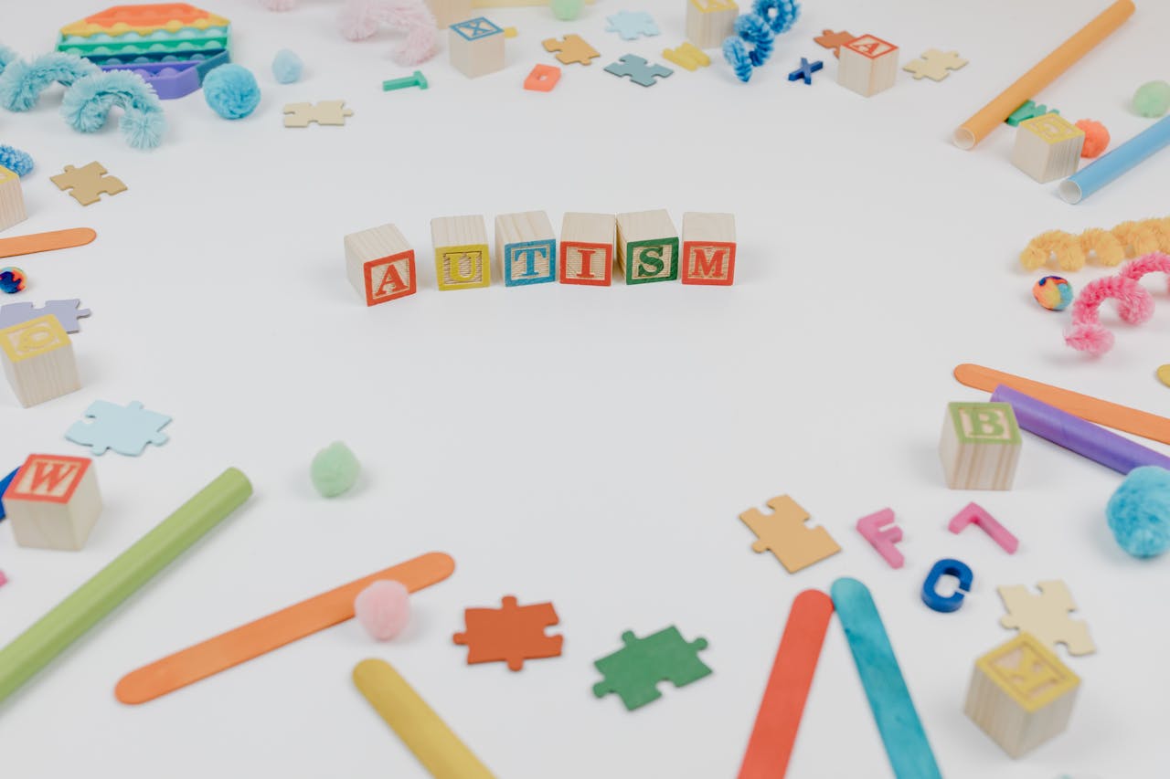 Colorful toys and puzzle pieces symbolizing autism awareness on a white background.